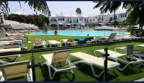 Un grupo de sillas de jardín y una piscina. en Home Wellness, en Playa del Inglés