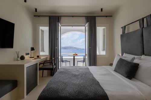 a bedroom with a bed and a desk and a table at Rocabella Mykonos Hotel in Agios Stefanos