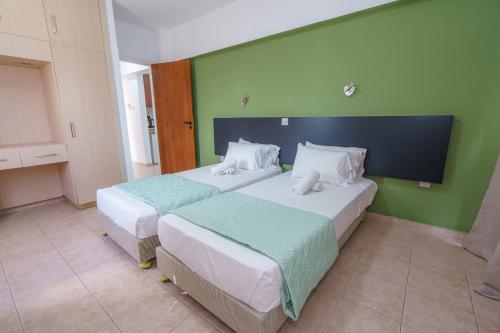 two beds in a room with green walls at Pernera One Suites in Pernera Protaras in Paralimni