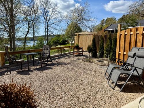 a patio with chairs and a table and a fence at Hällesdalens Gård - semesterhus i Bohuslän in Svenshögen