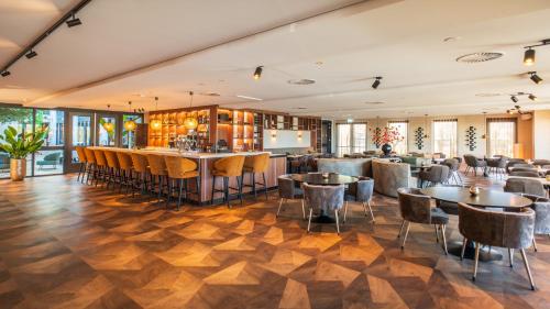 a restaurant with tables and chairs and a bar at Eilandhotel Texel - Nieuw geopend hotel in De Cocksdorp