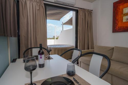 a table with two wine glasses and a couch at Pernera One Suites in Pernera Protaras in Paralimni