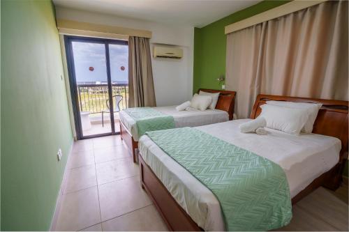 a hotel room with two beds and a balcony at Pernera One Suites in Pernera Protaras in Paralimni