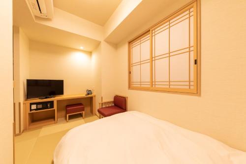 a bedroom with a bed and a tv and a window at Onyado Nono Asakusa Natural Hot Spring in Tokyo