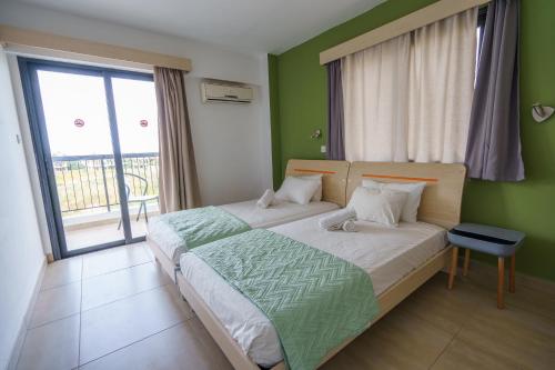 a bedroom with a bed with green walls and a window at Pernera One Suites in Pernera Protaras in Paralimni