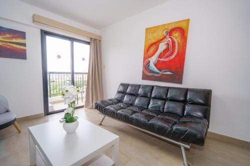 a living room with a leather couch and a table at Pernera One Suites in Pernera Protaras in Paralimni