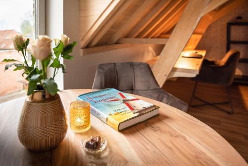 a table with a book and a vase with flowers at B&B 't Molenerf in Wingene