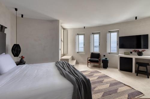 a bedroom with a bed and a tv and a chair at Rocabella Mykonos Hotel in Agios Stefanos