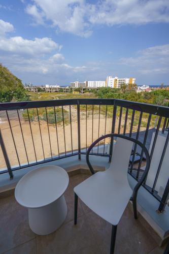 a white table and a chair on a balcony at Pernera One Suites in Pernera Protaras in Paralimni