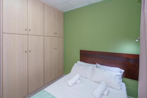 a bedroom with a bed with a wooden headboard and cabinets at Pernera One Suites in Pernera Protaras in Paralimni