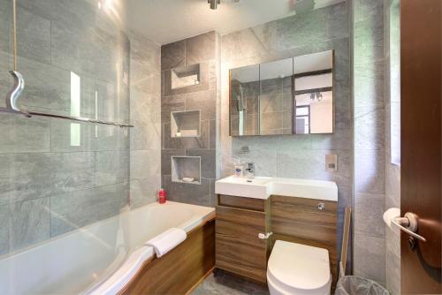 a bathroom with a tub and a sink and a toilet at Modern and Spacious 3 Bedroom Home in Peterborough in Peterborough