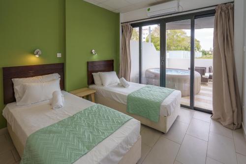 two beds in a room with green walls at Pernera One Suites in Pernera Protaras in Paralimni