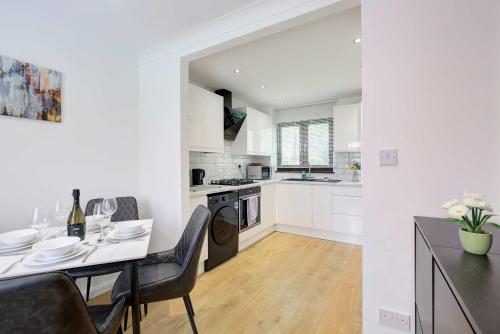 a white kitchen with a table and a dining room at Modern and Spacious 3 Bedroom Home in Peterborough in Peterborough