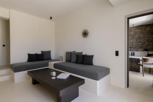 a living room with two beds and a table at Rocabella Mykonos Hotel in Agios Stefanos