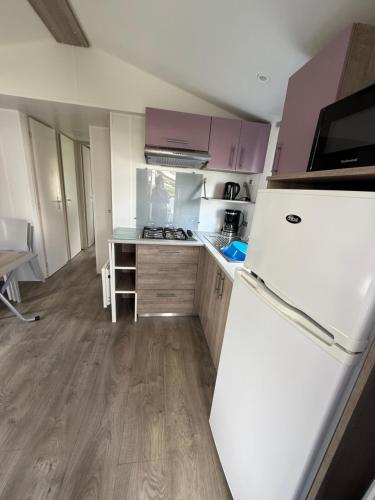 Il comprend une cuisine équipée d'un réfrigérateur blanc. dans l'établissement Mobil home, à Saint-Nic