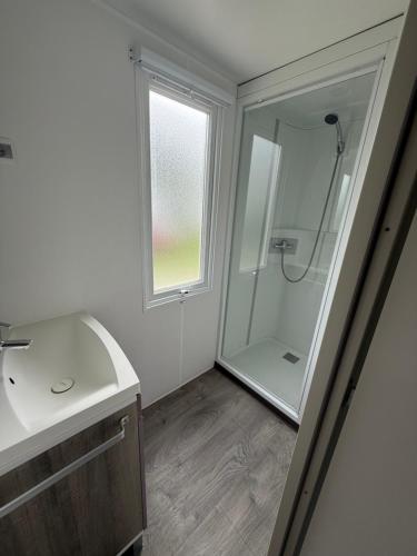 une salle de bain blanche avec une douche et un lavabo dans l'établissement Mobil home, à Saint-Nic