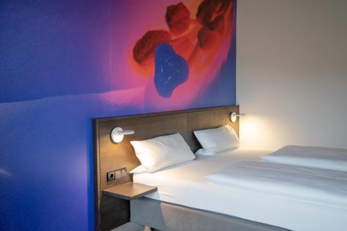 a bedroom with a bed with a painting on the wall at qubixx stadtmittehotel in Schwäbisch Hall