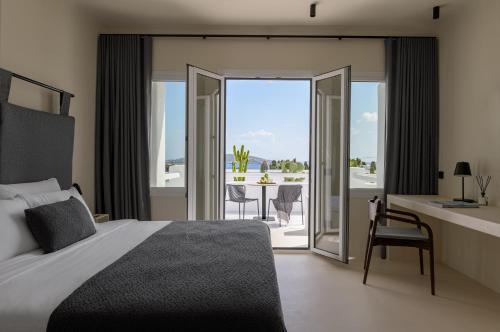 a bedroom with a bed and a view of a patio at Rocabella Mykonos Hotel in Agios Stefanos