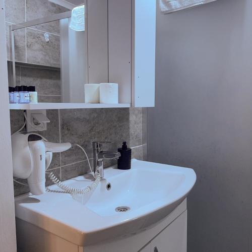 a bathroom with a white sink and a mirror at Hera Pansiyon in Ayvalık