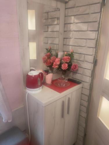 a small cabinet with flowers on top of it at Pokój dla jednej osoby z łazienką in Gniezno