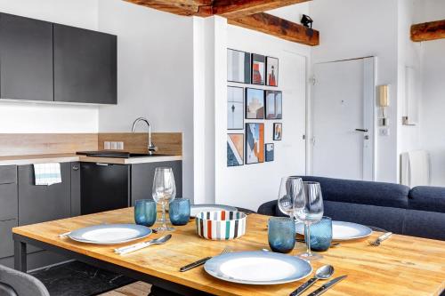 une table en bois avec des assiettes et des verres à vin dessus dans l'établissement Un Eclat de Lumiere en Plein Paris, à Paris