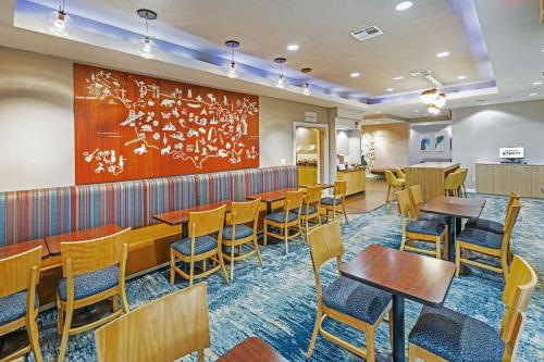 a restaurant with wooden tables and chairs and a large wall at TownePlace Suites by Marriott Tulsa Broken Arrow in Broken Arrow