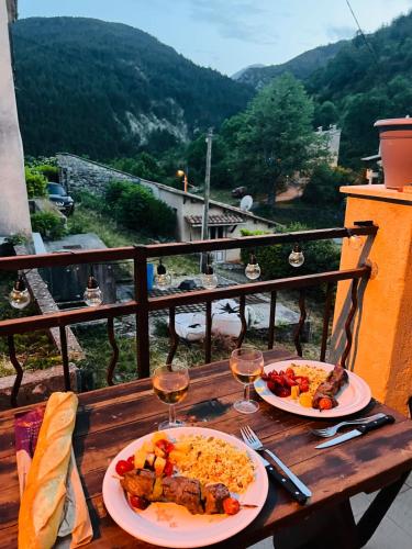 - une table en bois avec 2 assiettes de nourriture et des verres à vin dans l'établissement Maison de village Provençale, à Ubraye