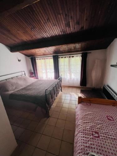 une chambre avec deux lits et un plafond en bois dans l'établissement Maison de village Provençale, à Ubraye