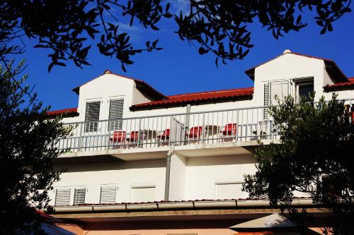 a white building with red chairs on a balcony at Panorama Apartments in Povljana