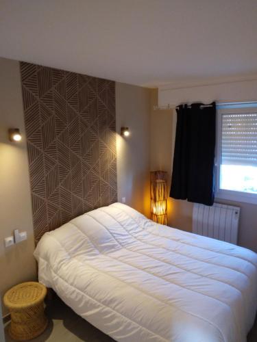 a bedroom with a large white bed with a window at Résidence T2 , Jardin 100m plage Parking gratuit in Valras-Plage