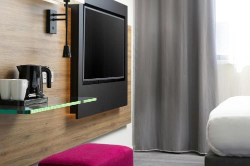 a hotel room with a tv and a bed at Moxy Southampton in Southampton