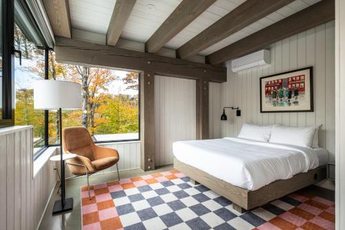 a bedroom with a bed and a chair and a window at NEW! Lagom Tyst Chalet 7 Bedroom Hot Tub Near Resort in Mont-Tremblant