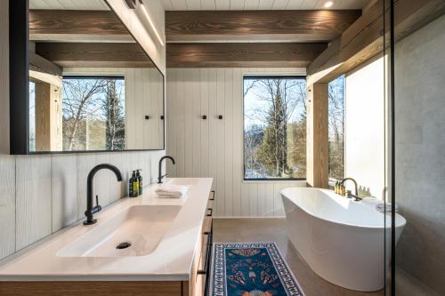 a bathroom with a tub and a sink and a mirror at NEW! Lagom Tyst Chalet 7 Bedroom Hot Tub Near Resort in Mont-Tremblant