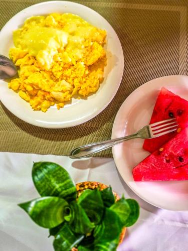 two plates of scrambled eggs and a bowl of watermelon at Vila Sancar Pousada in Lençóis