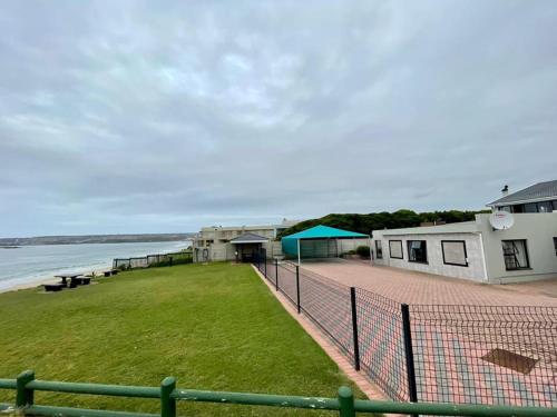 a building with a fence next to the water at Bayview Seefront Accommodation in Mossel Bay