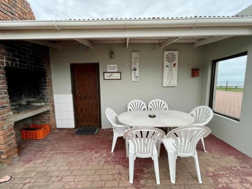a white table and chairs on a patio at Bayview Seefront Accommodation in Mossel Bay