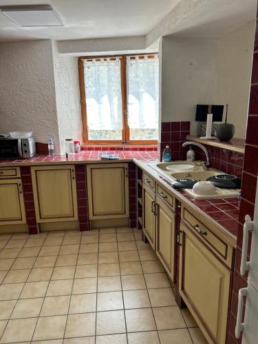 une cuisine avec des armoires jaunes et des sols en carrelage rouge dans l'établissement Maison de village typique, à Meysse