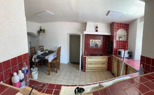 une cuisine avec des carreaux rouges sur les murs et une table dans l'établissement Maison de village typique, à Meysse