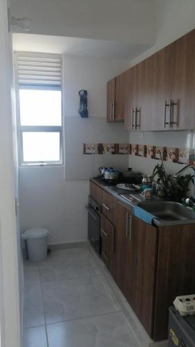eine Küche mit Holzschränken, Spüle und Fenster in der Unterkunft Curinca in Santa Marta