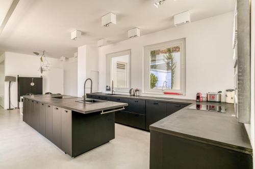 Una cocina grande con gabinetes negros y un fregadero. en Villa Kryvo - Quiet retreat, en Kóstos