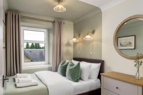 a bedroom with a bed with a mirror and a window at Central Cathedral Apartment in Dunblane