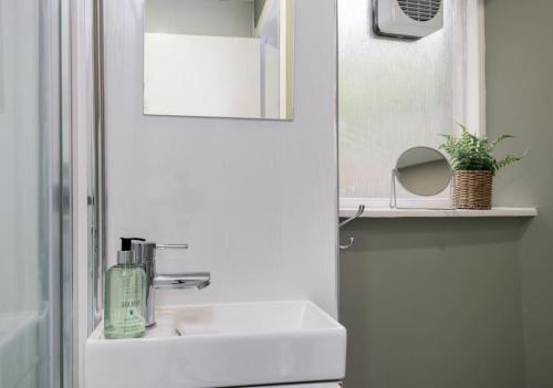 a white bathroom with a sink and a mirror at Central Cathedral Apartment in Dunblane