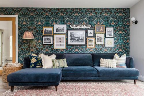 a blue couch in a living room with a wall at Brunstane House - 15 mins to City Centre in Edinburgh