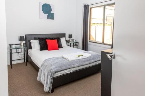 a bedroom with a bed with a red pillow and a window at Riverview- Modern 3 Bedroom sleeps 2-8 in Gawler