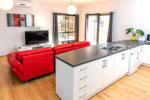 a kitchen with two red chairs and a kitchen island at Riverview- Modern 3 Bedroom sleeps 2-8 in Gawler