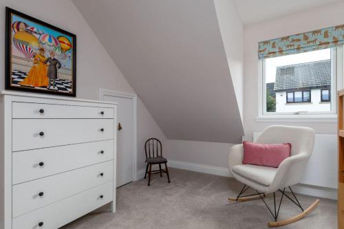 a bedroom with a white dresser and a chair at Brunstane House - 15 mins to City Centre in Edinburgh