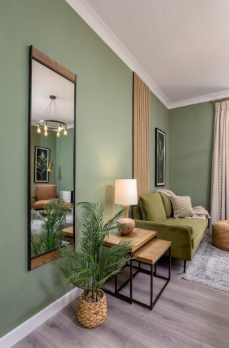 a living room with a green couch and a mirror at Ochill View Apartment by Stirling Train Station in Stirling