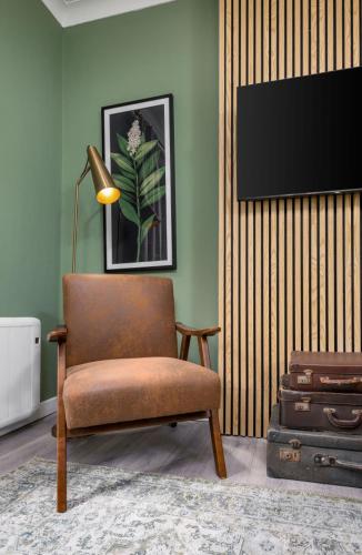a living room with a chair and a flat screen tv at Ochill View Apartment by Stirling Train Station in Stirling