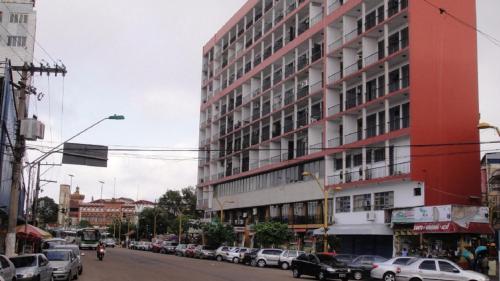 un edificio rojo en una calle de la ciudad con coches aparcados en Ajuricaba Suítes 8, en Manaus