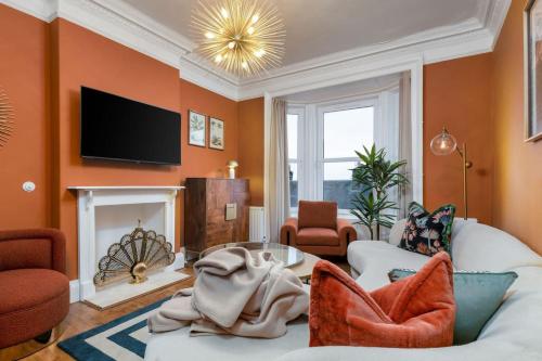 a living room with orange walls and a fireplace at Stylish Penthouse Retreat in Stirling